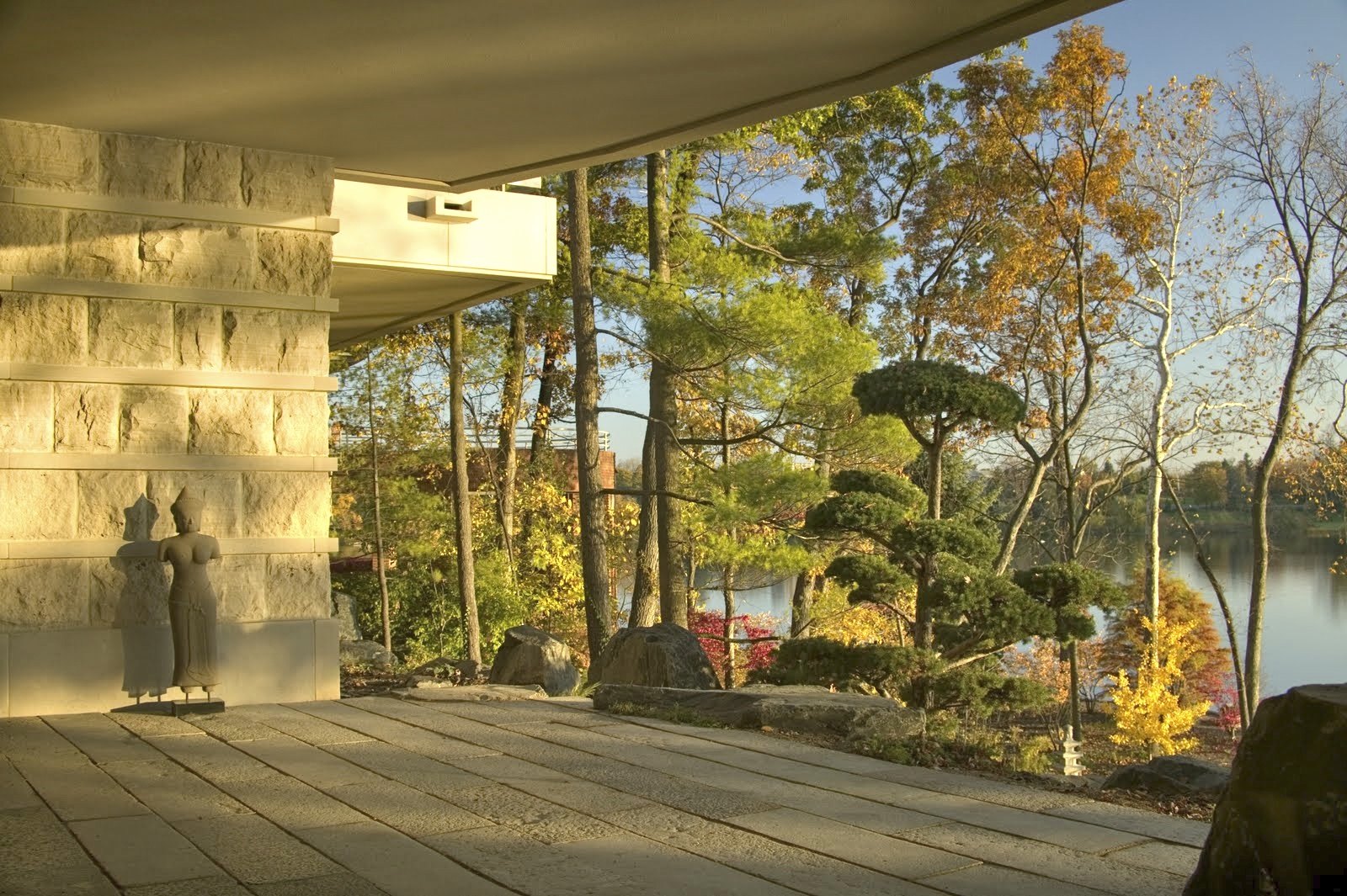 The covered terrace, with a stone figure and the lake through the pines