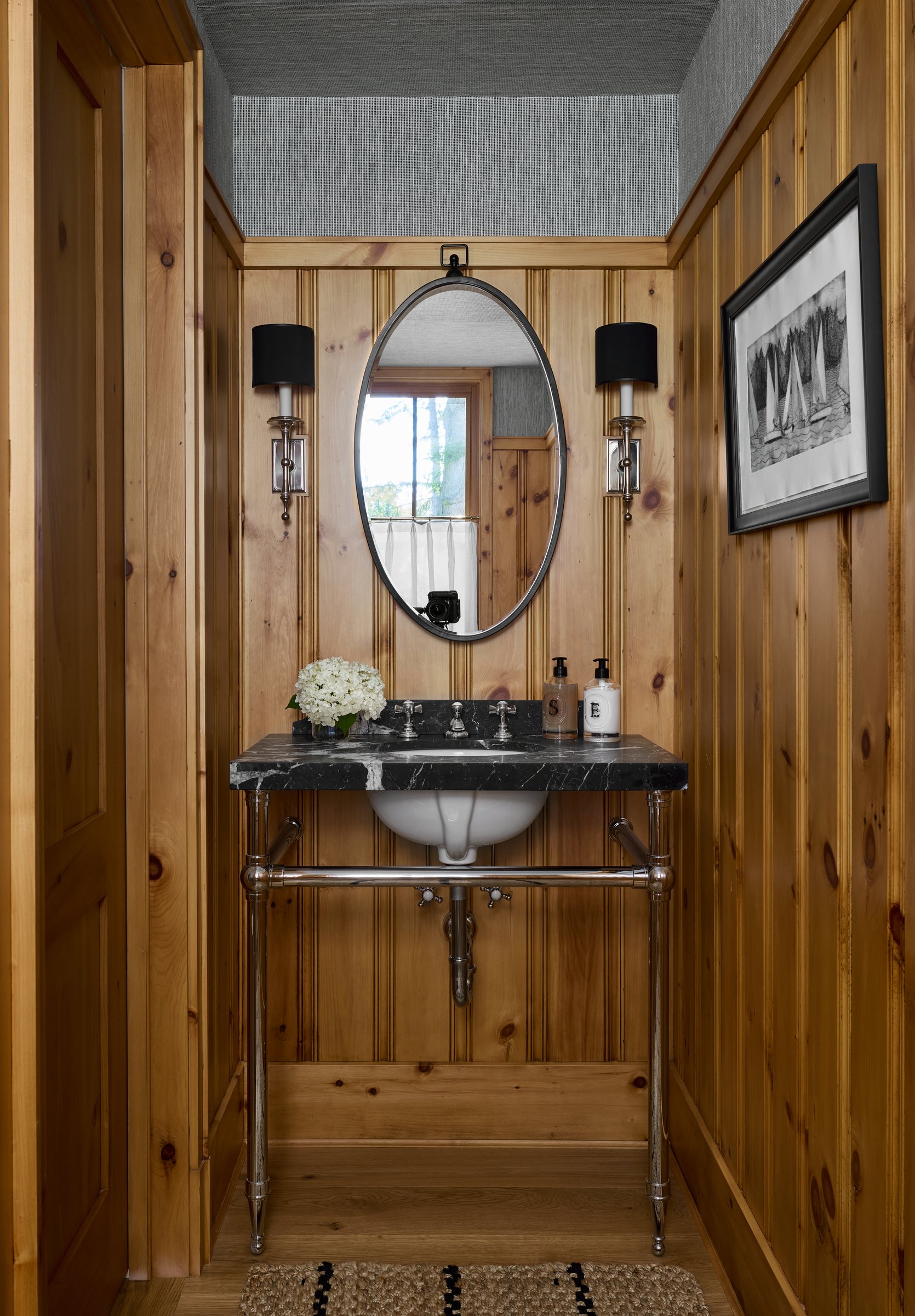 Cedar-paneled powder room with an oval mirror