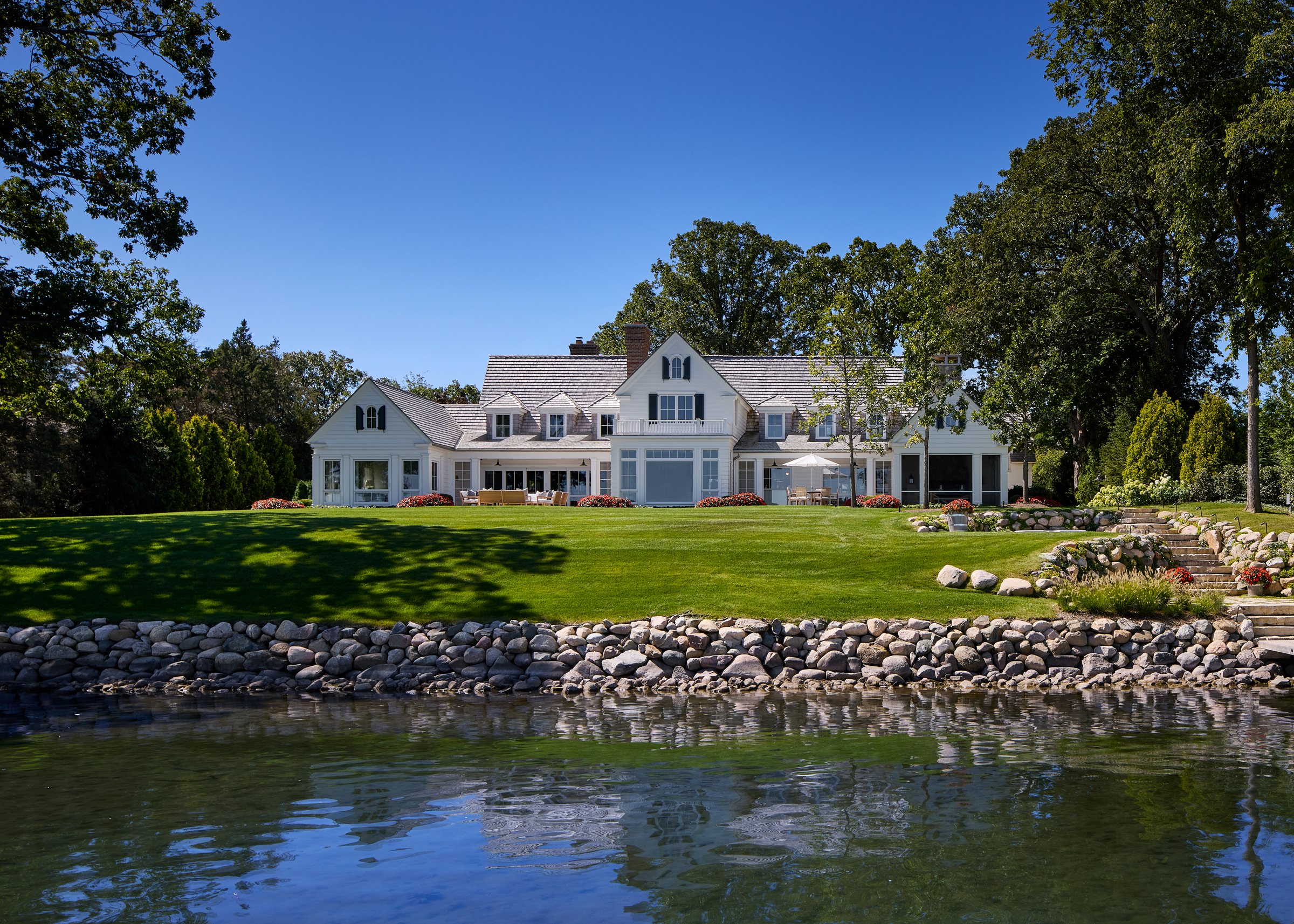 Shingle-style lakefront cottage with porches facing the water