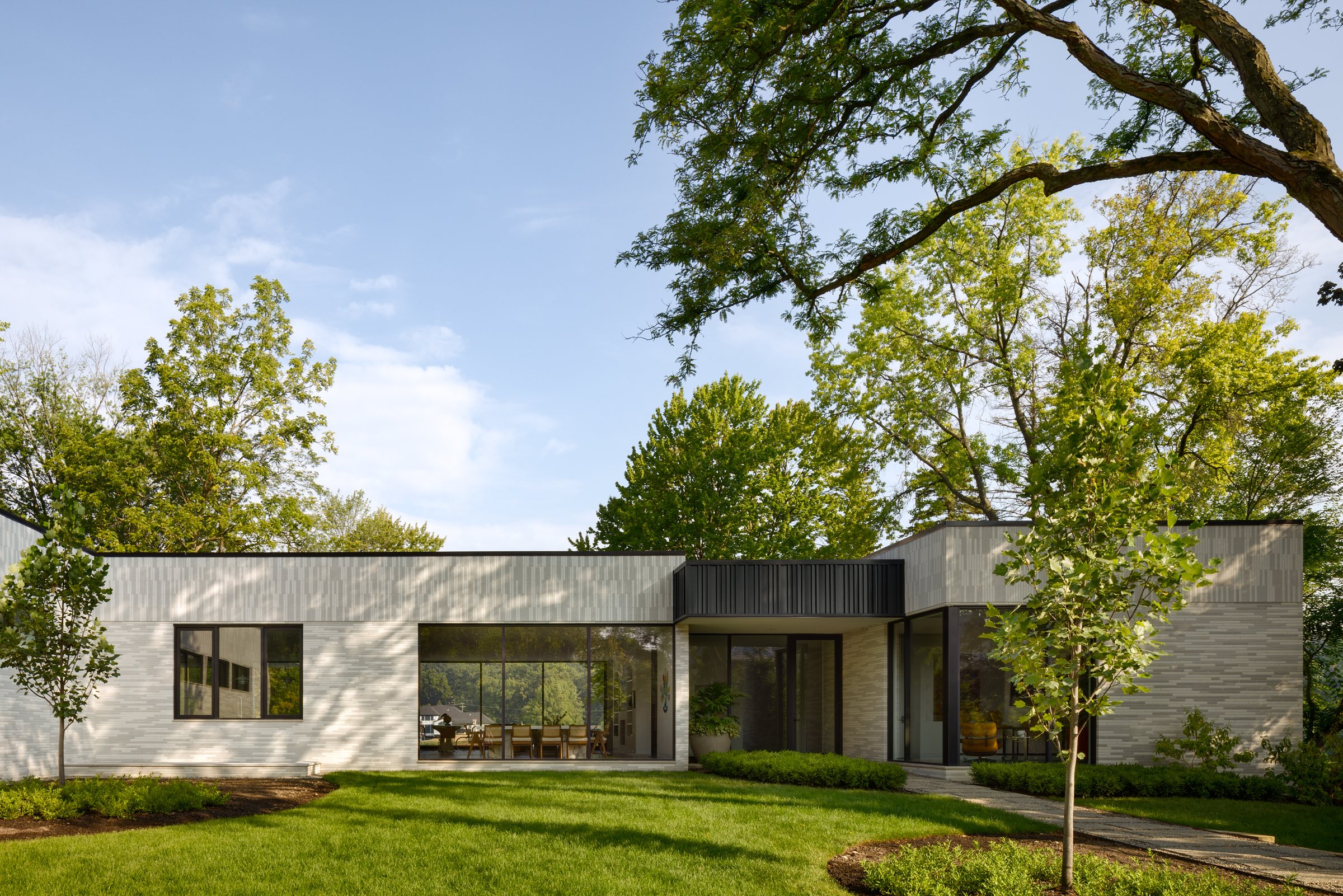 Low modern lakefront house in custom brick and glass among old trees
