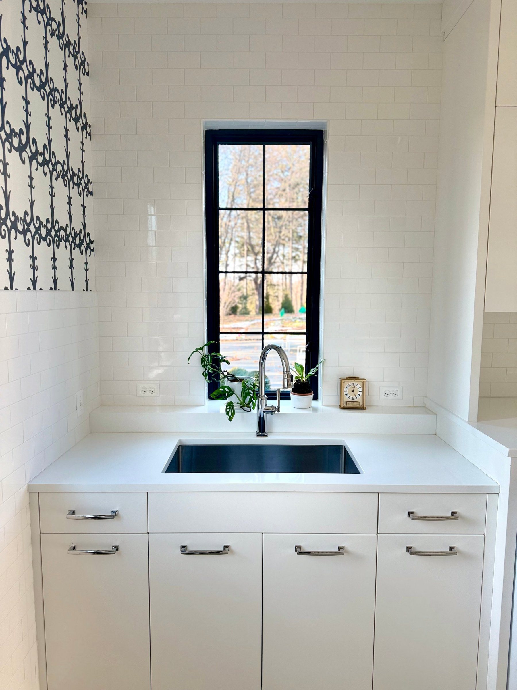 White laundry room with a steel window centered over the sink