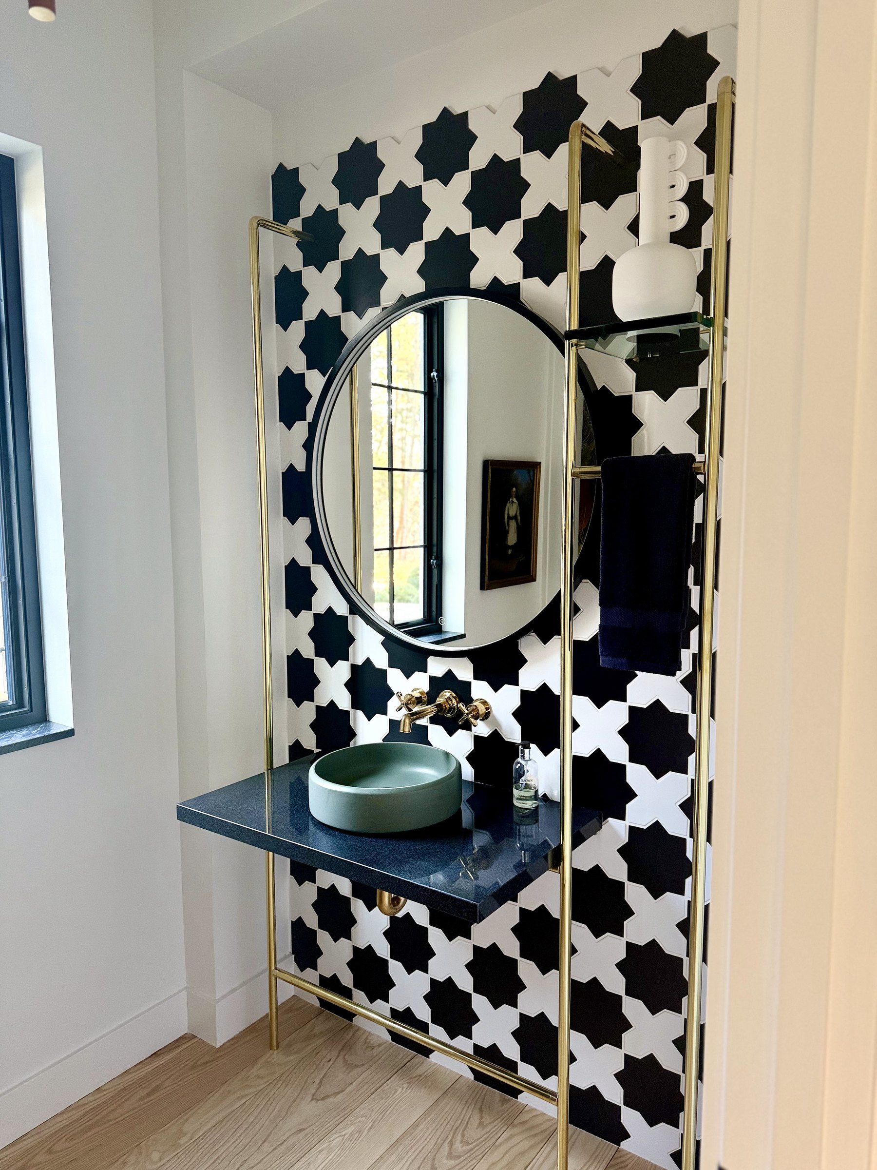 Powder room with a black-and-white star tile wall and brass fittings