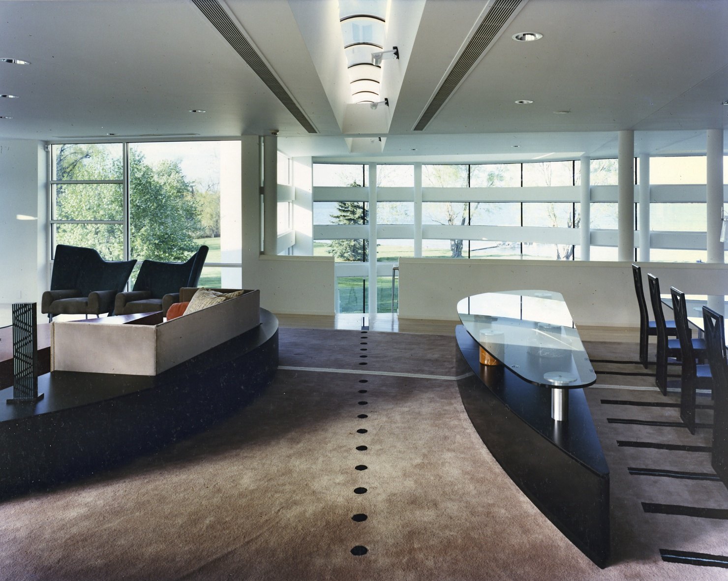 The main living room: a raised black granite deck, a boat-shaped glass table, and the lake beyond