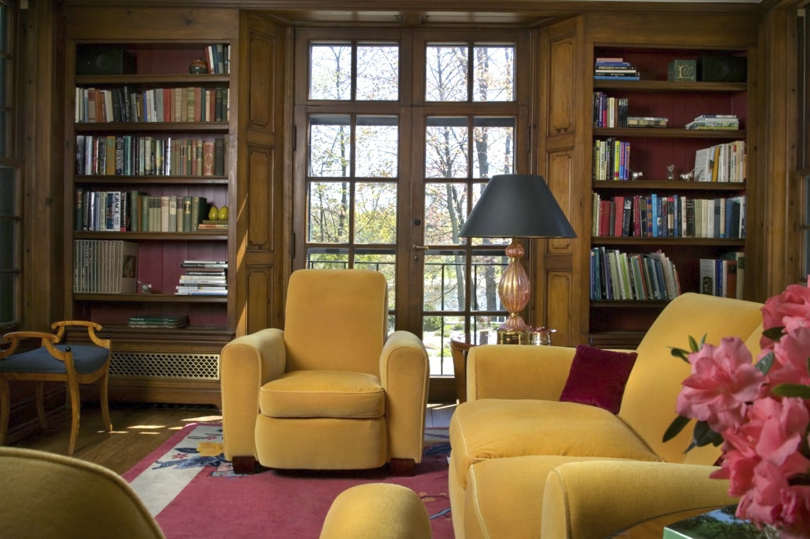 The library: paneled walls, bookcases, and French doors to the garden