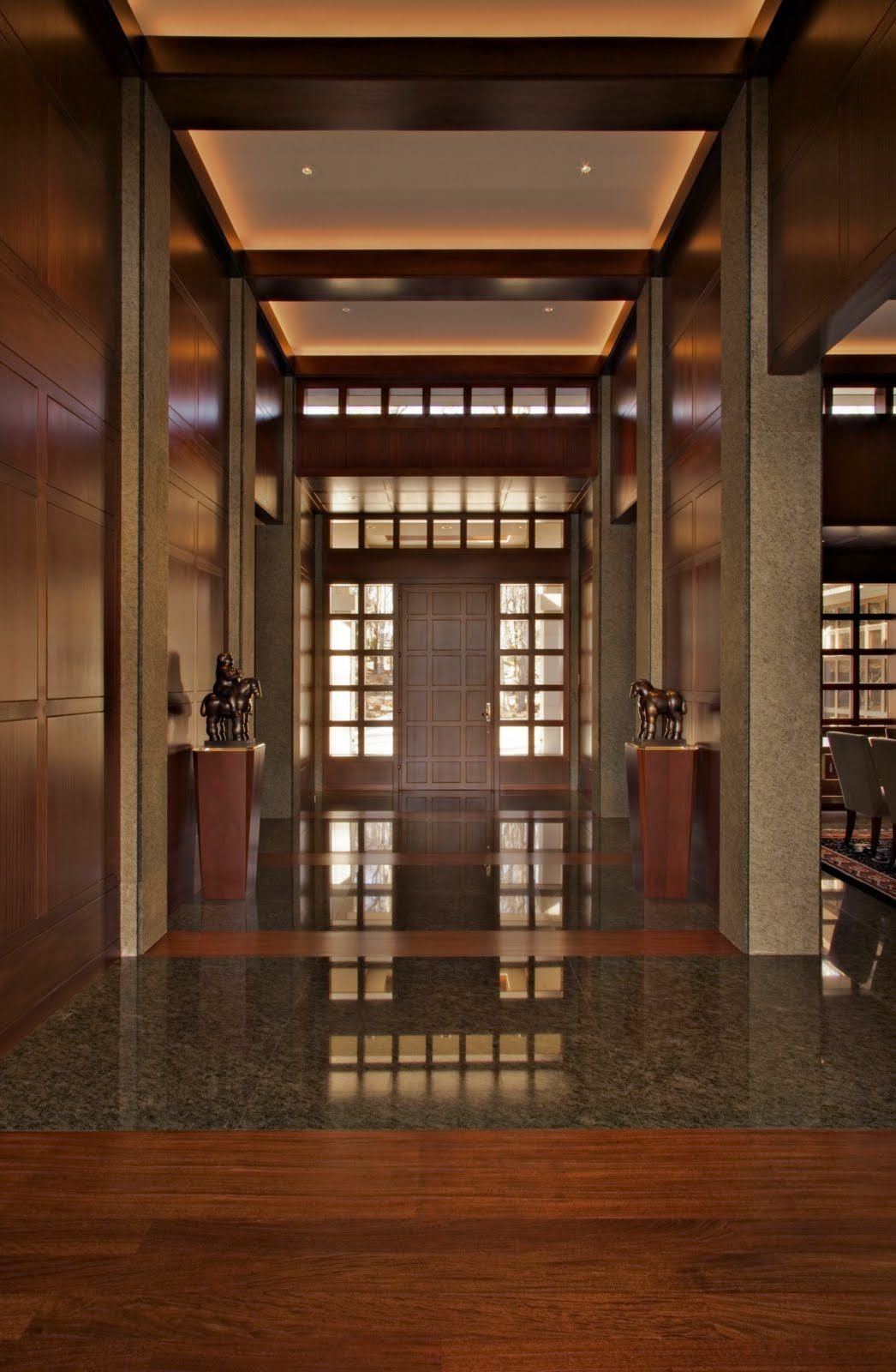 The entry hall: granite piers, mahogany, and a lit coffered ceiling