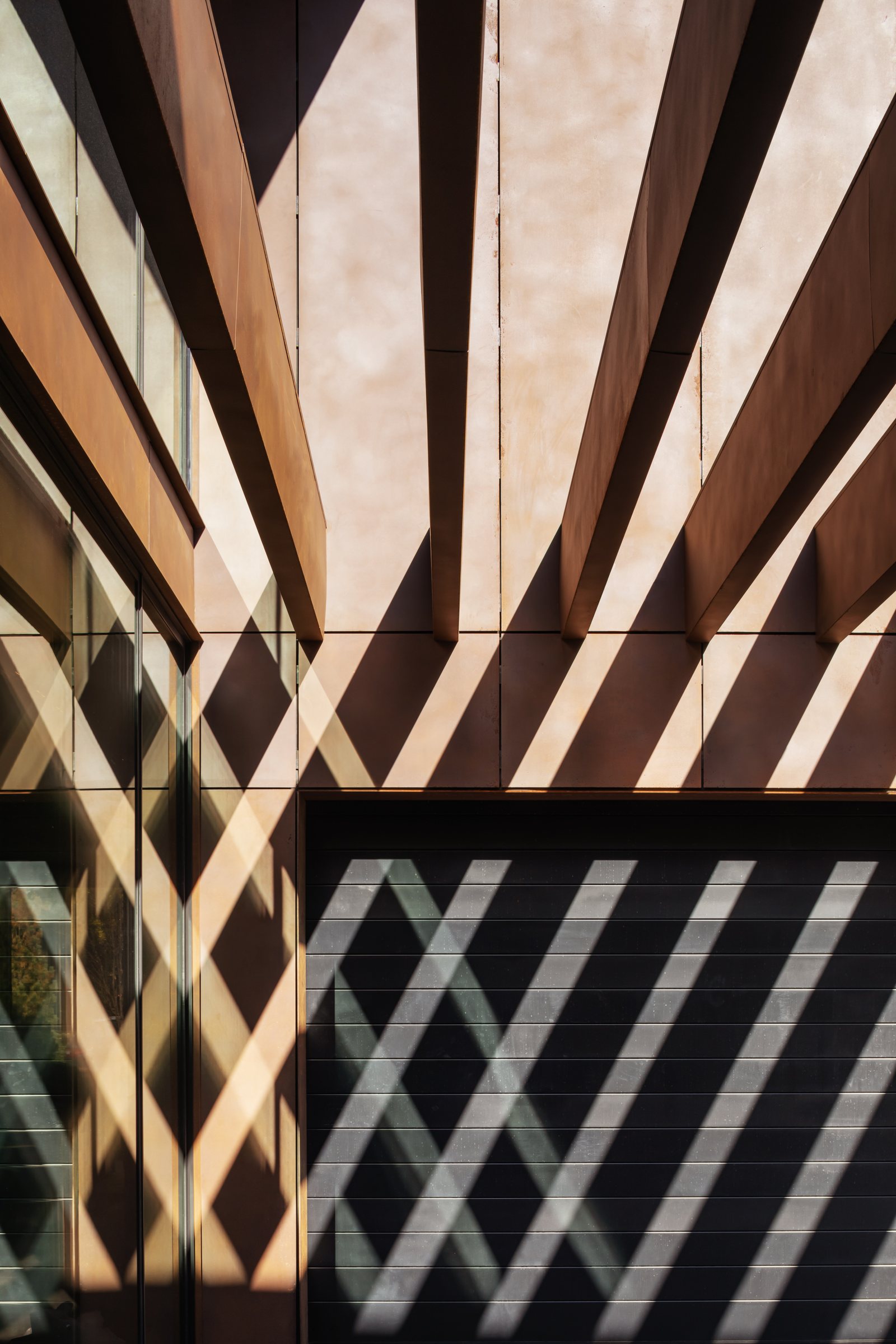 Weathered steel screen casting a diagonal shadow across a wall
