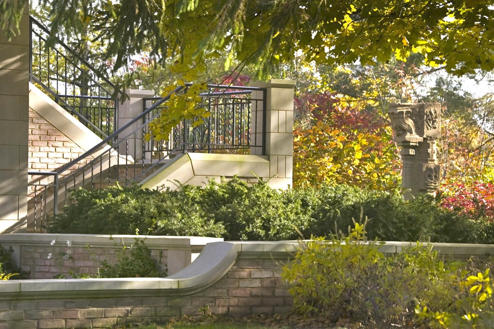 A garden stair with iron railings, limestone walls, and a carved stone column from India