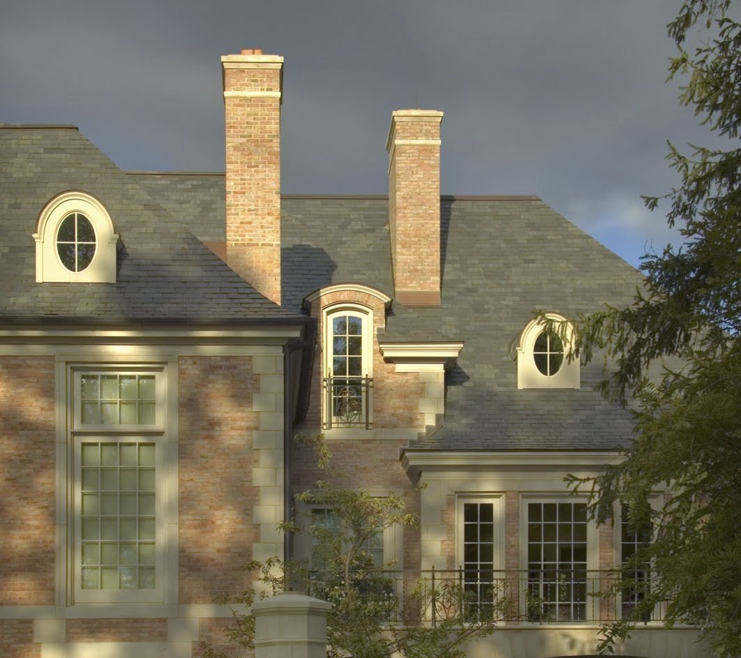Chimneys and dormers in the slate roof above a balconied window