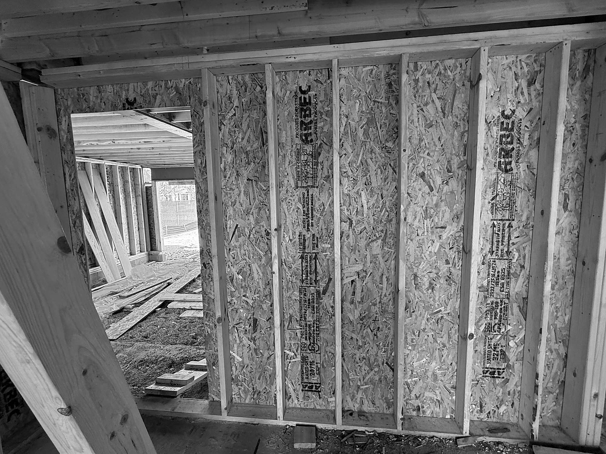 Wall sheathing before insulation. Sheathing carries structure and, with its seams detailed, can form part of the air barrier.
