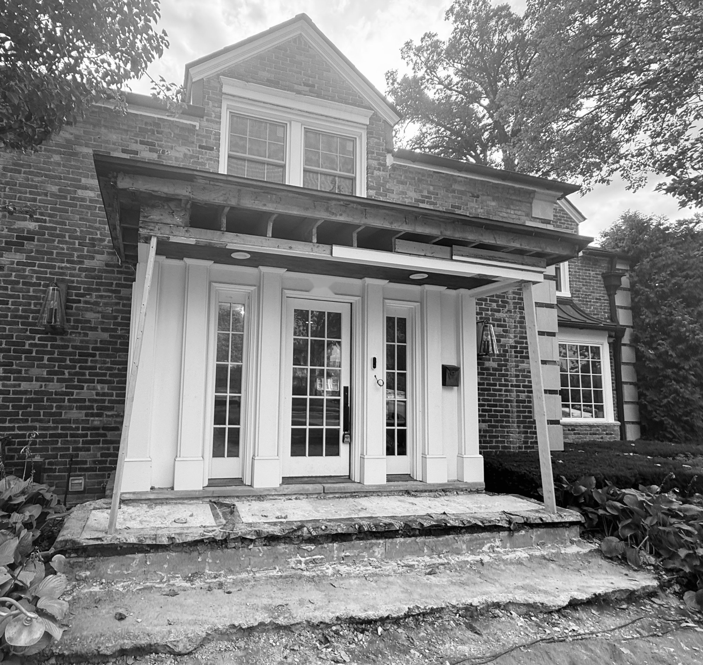 The portico stripped to its framing, the roof on temporary posts, and the old steps removed.