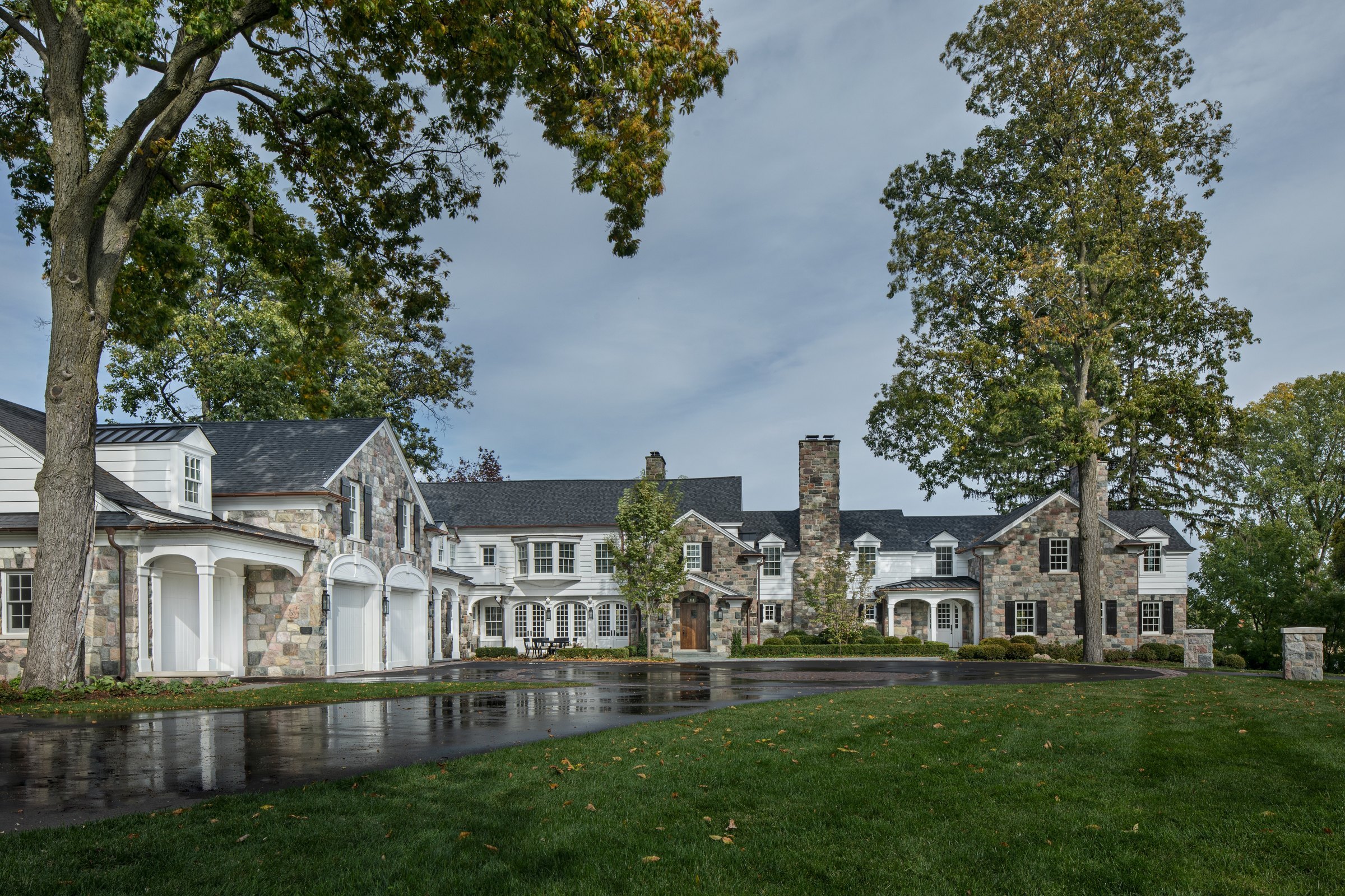 A stone house with a long, ordered front: gables, chimneys and windows set in a consistent rhythm across the elevation.
