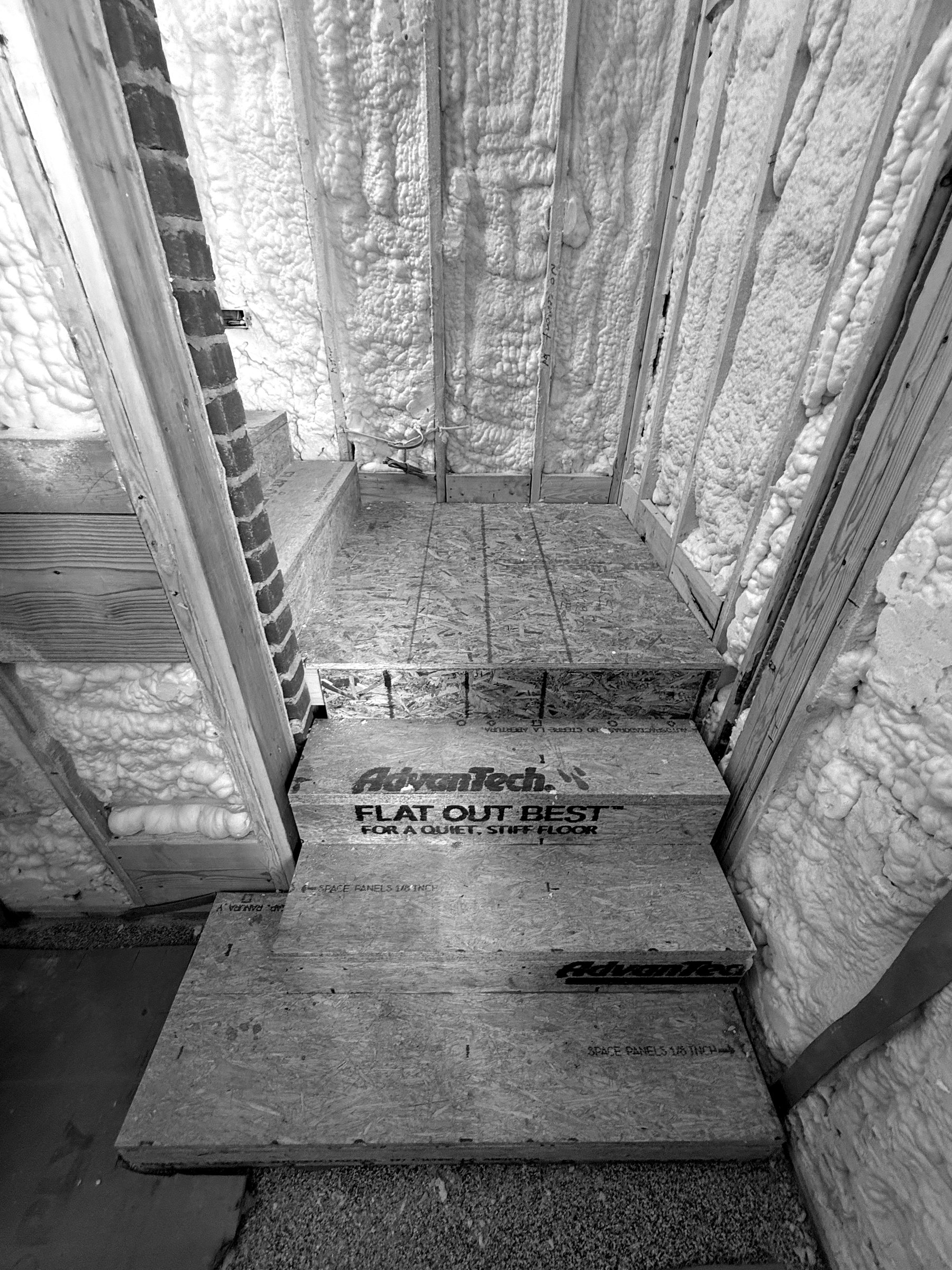 Foam on the walls and roof above a stair, sealed tight against the brick and around irregular framing.