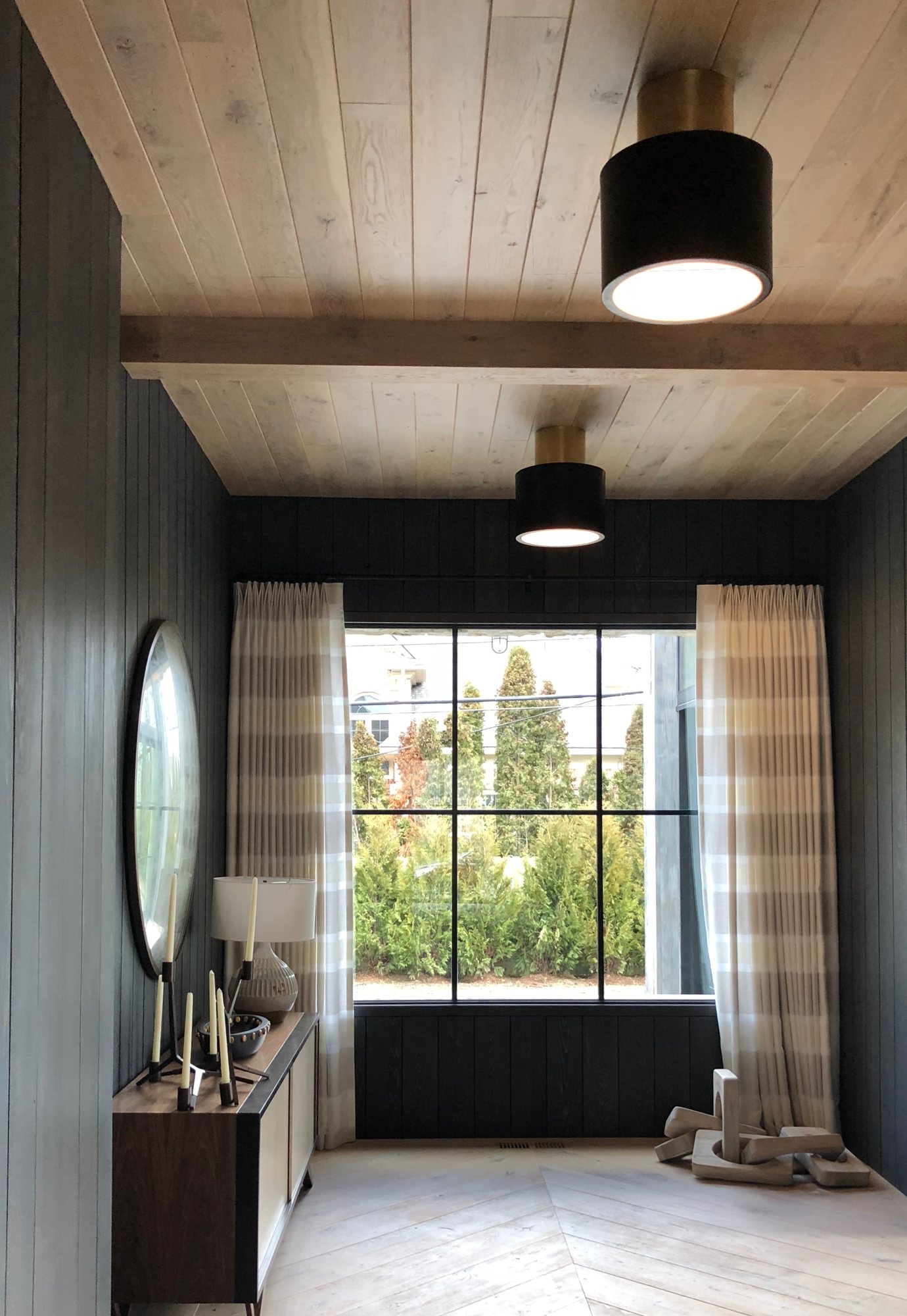 Vestibule with black shiplap walls, pale oak ceiling, and a steel window