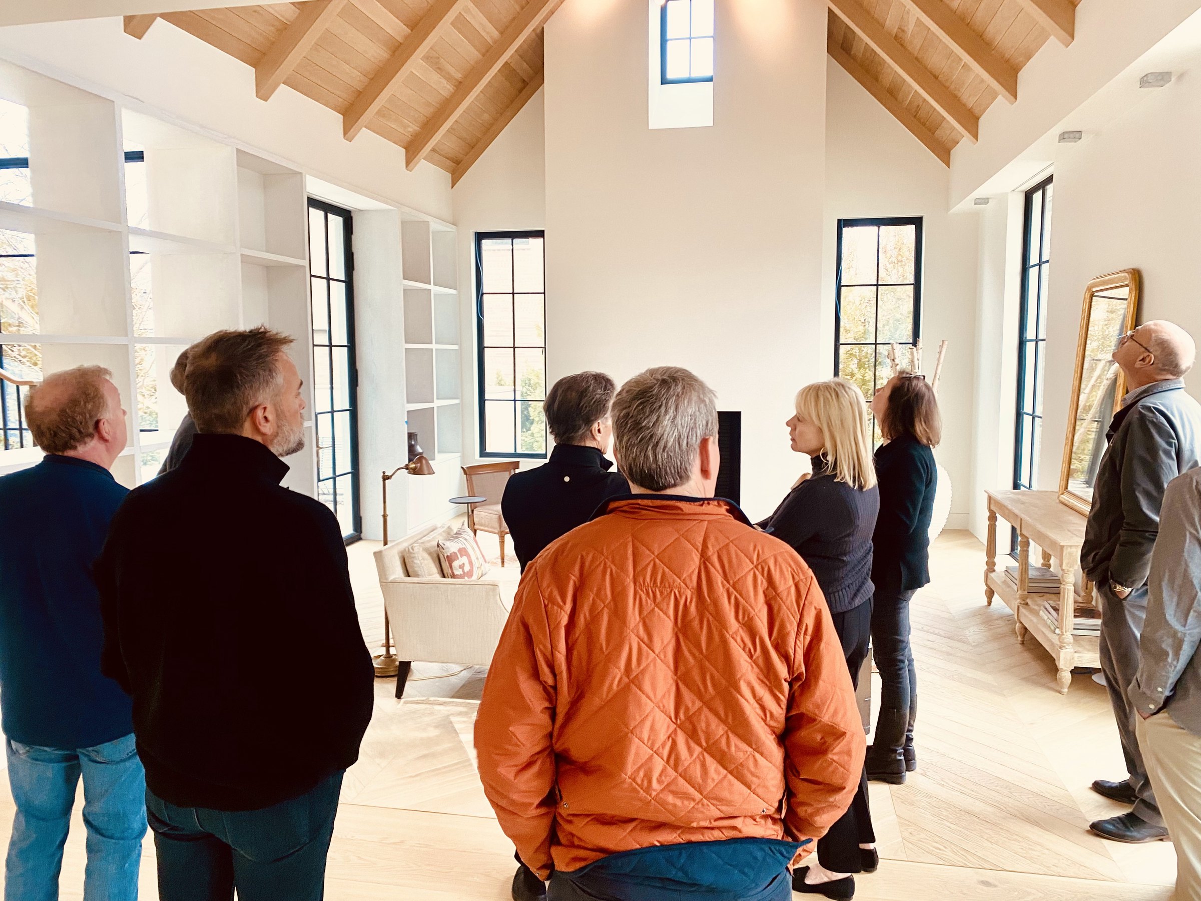 The team and clients walking a nearly finished room with a vaulted wood ceiling